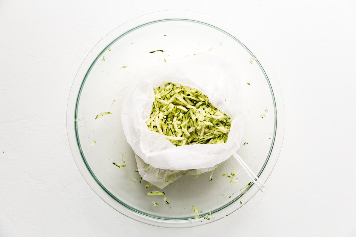 zucchini and onion in a nut bag over a bowl