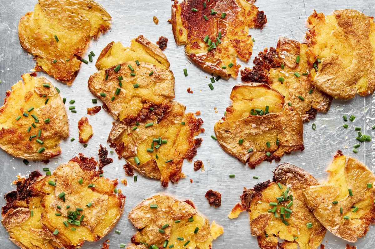 crispy smashed potatoes seasoned with salt and garlic sprinkled and with chives on a baking sheet