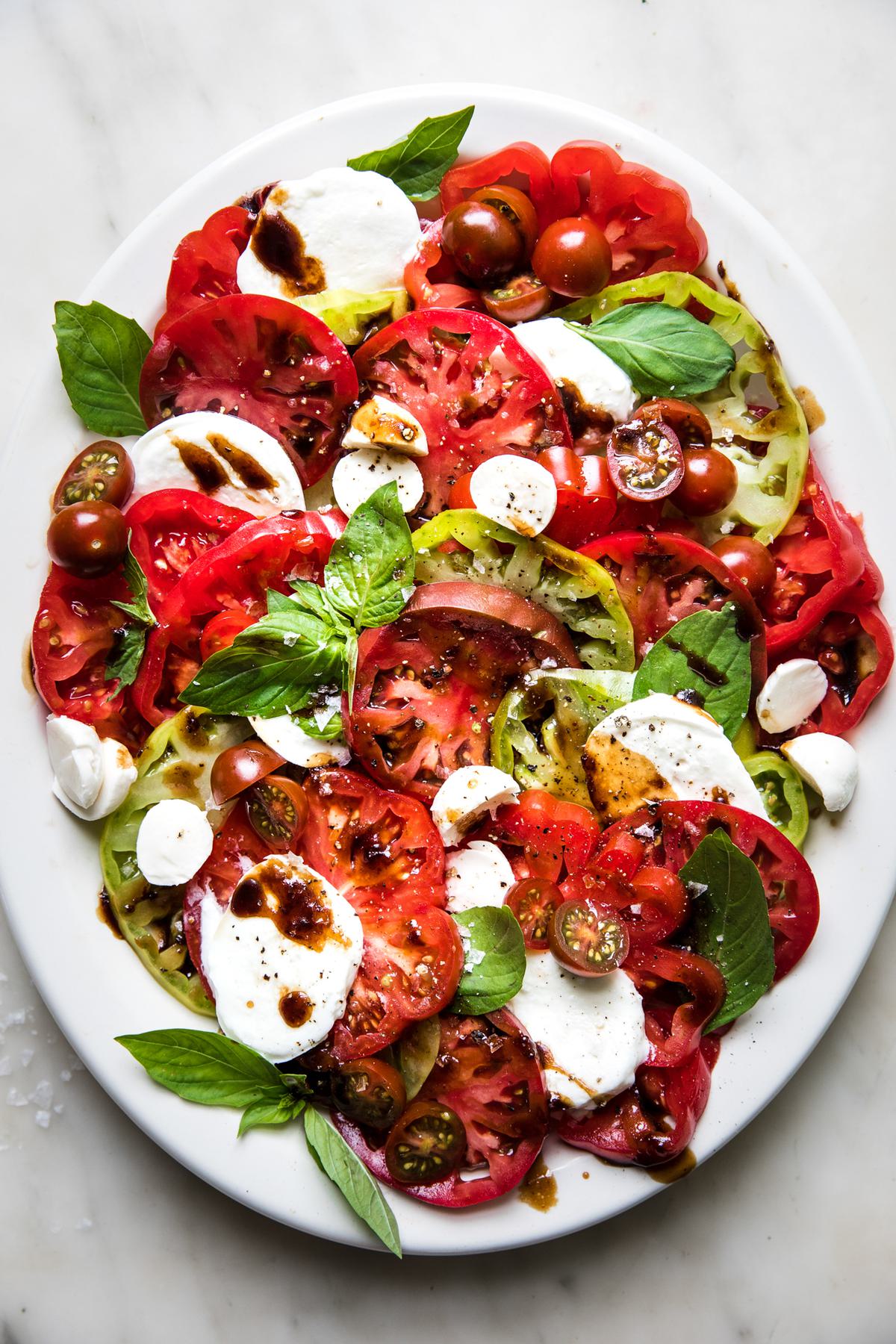 homemade caprese salad with fresh mozzarella, basil and heirloom tomatoes drizzled in a balsamic vinegar glaze
