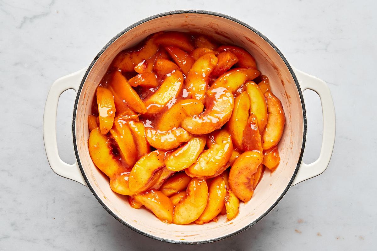 peaches being stirred in a pot with a slurry made of peach juice, vanilla, lemon juice, spices, and cornstarch for peach pie