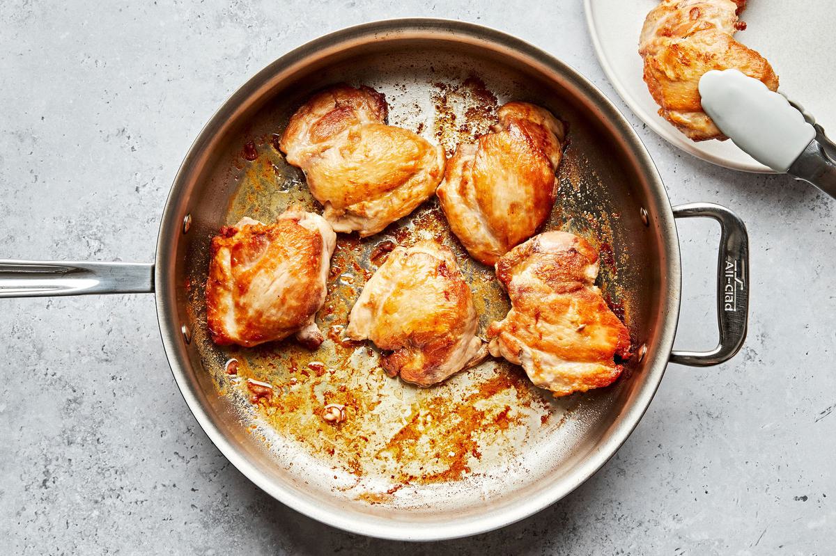 skinless chicken thighs seasoned with salt being browned in olive oil in a large pan