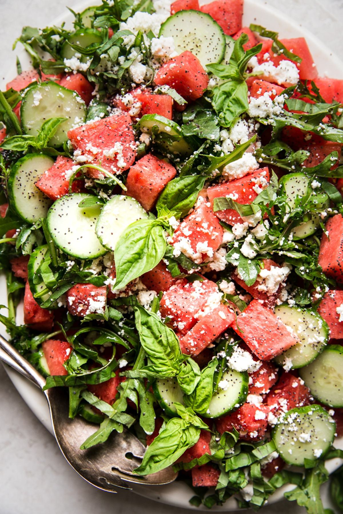 watermelon salad with cucumber, feta, basil and a poppyseed dressing on a plater